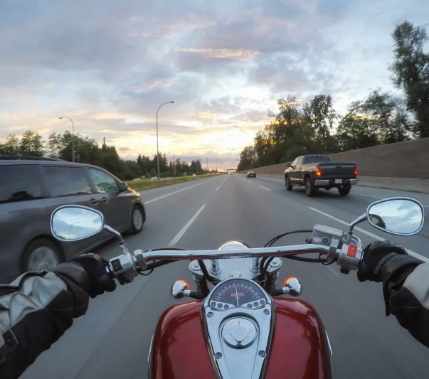 riding motorcycle next to vehicles during sunset