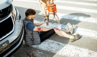 A man sitting on the road after an accident with bruise on the hand and leg