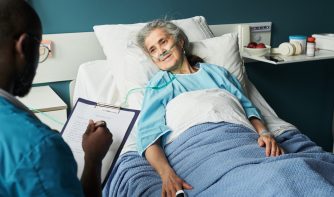 elderly woman in hospital bed talking to a nurse
