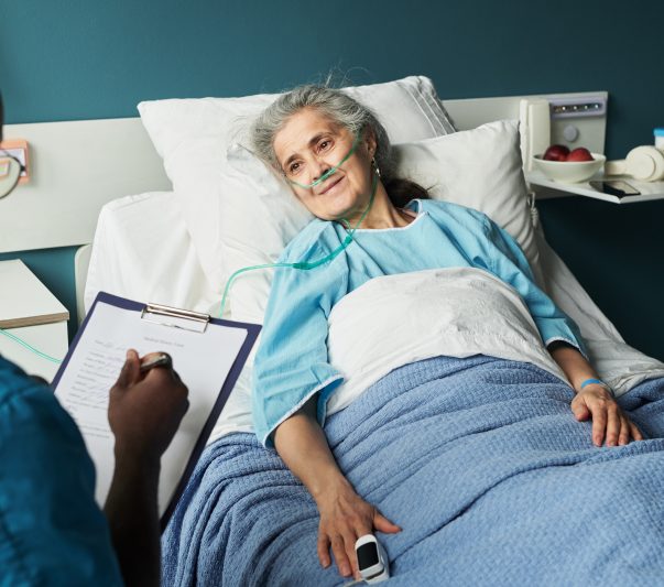 elderly woman in hospital bed talking to a nurse