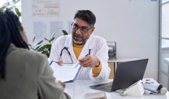 doctor holding clipboard discussing with patient