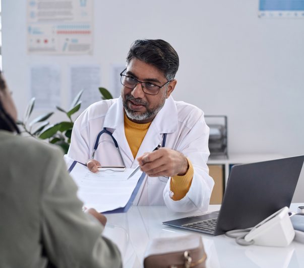 Senior Doctor Handing Clipboard to Patient doctor holding clipboard discussing with patient