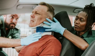 Two nurses helping a man with fix his neck