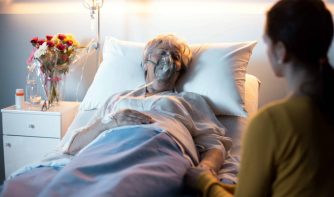 woman laying in hospital bed with a person visiting her