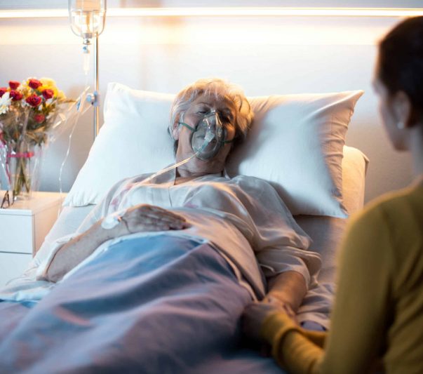 woman laying in hospital bed with a person visiting her