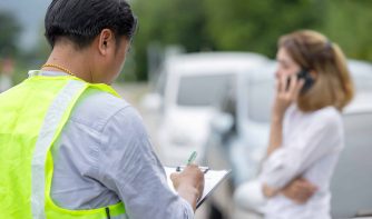 woman on the phone while person files a report for the car accident