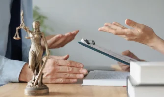 an attorney and a client discussing and a justice symbol on the table