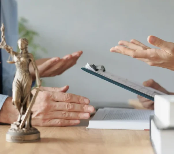 an attorney and a client discussing and a justice symbol on the table